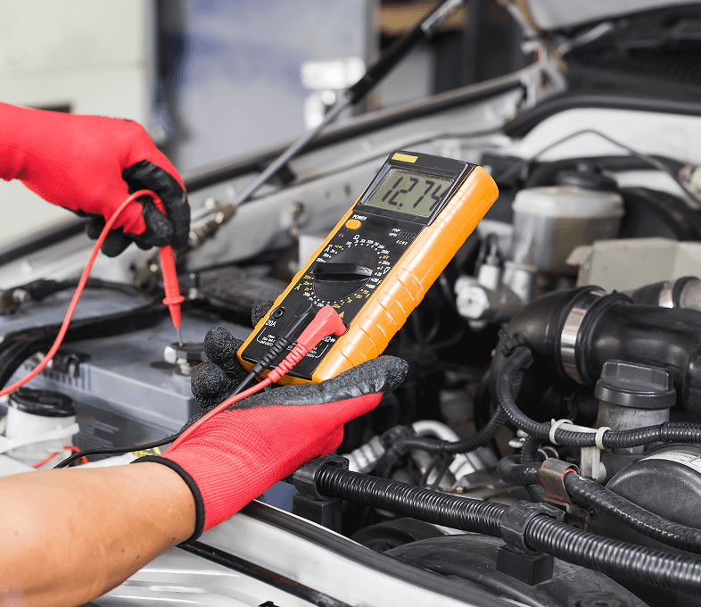 Mechanic using multimeter on car battery