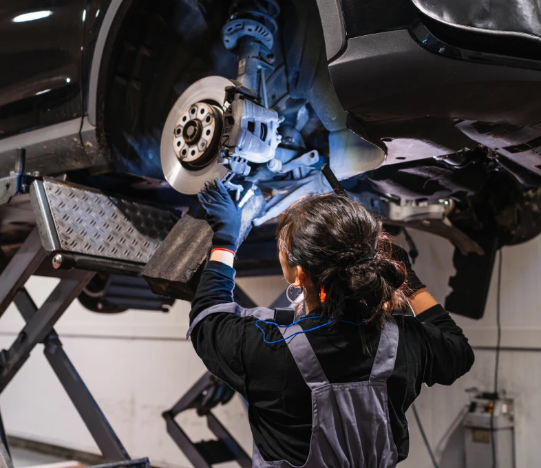 Technician repairing vehicle underside